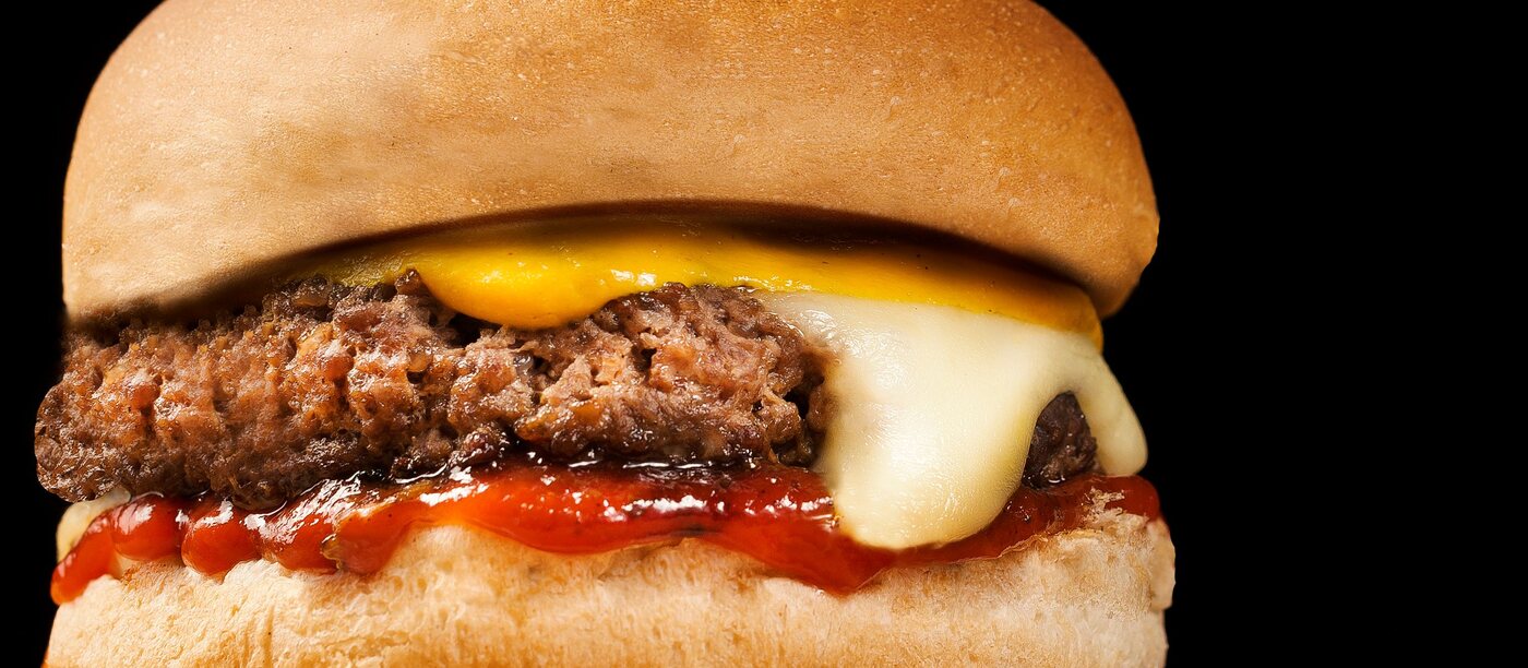 Cheeseburger met gesmolten kaas en ketchup in een broodje — representatief beeld.