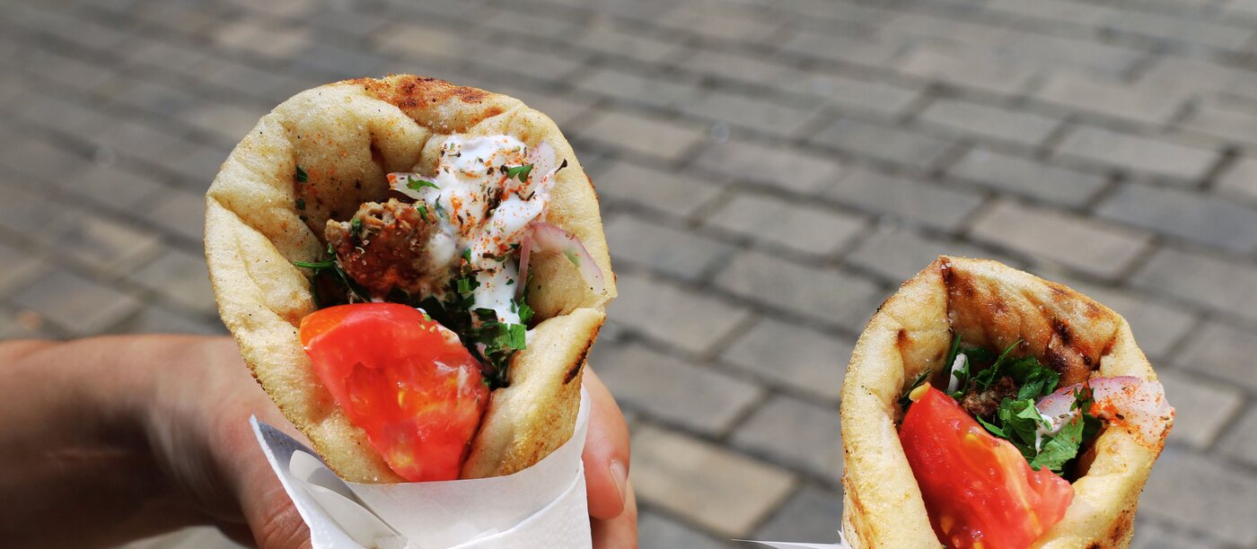 Twee pittabroodjes gevuld met gegrild vlees, tomaat en witte saus — representatief beeld.