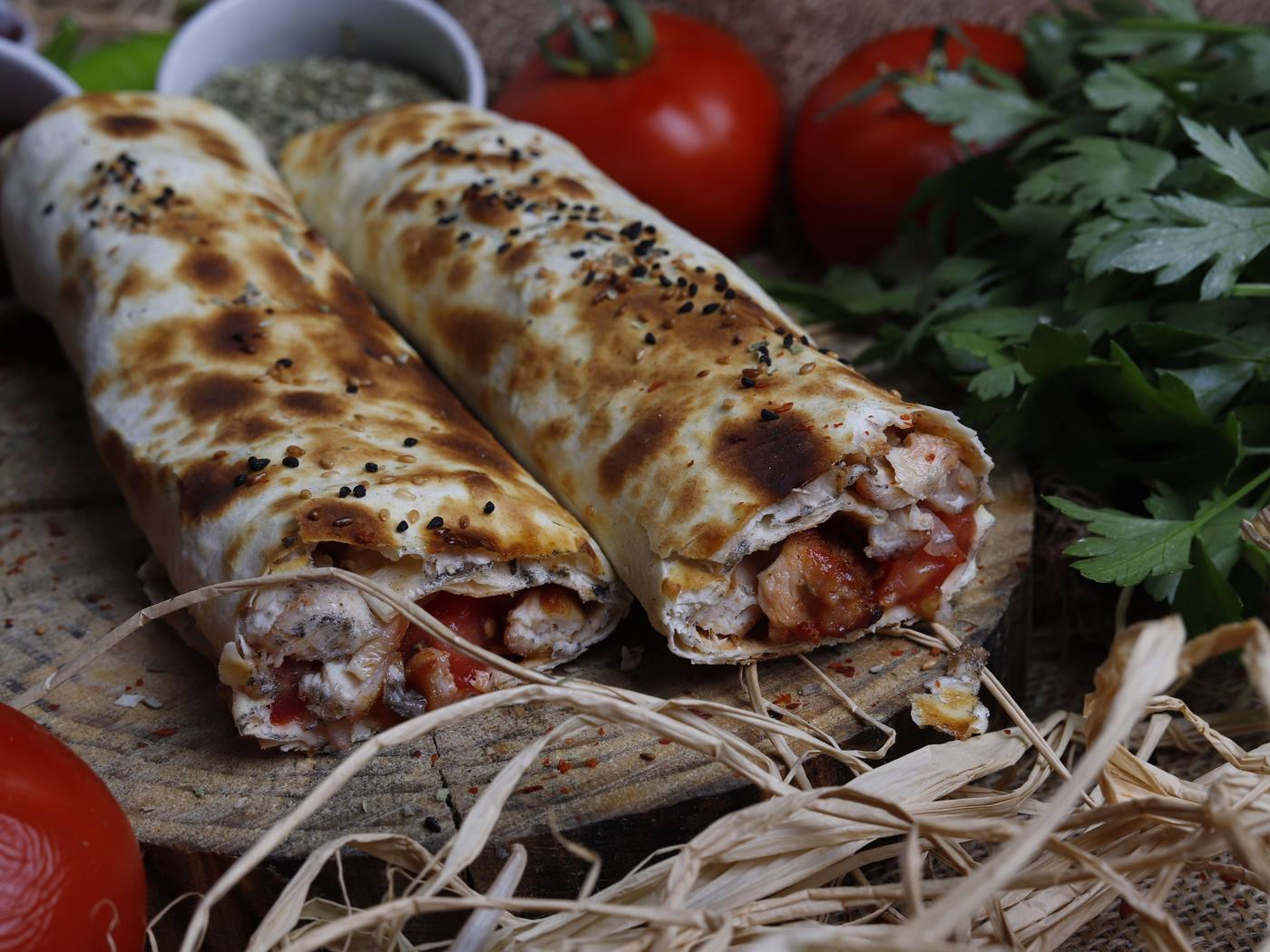 Gegrild gehaktspies op een houten plank met bulgur, lavash, kruiden en geroosterde groenten, van bovenaf — representatief beeld.